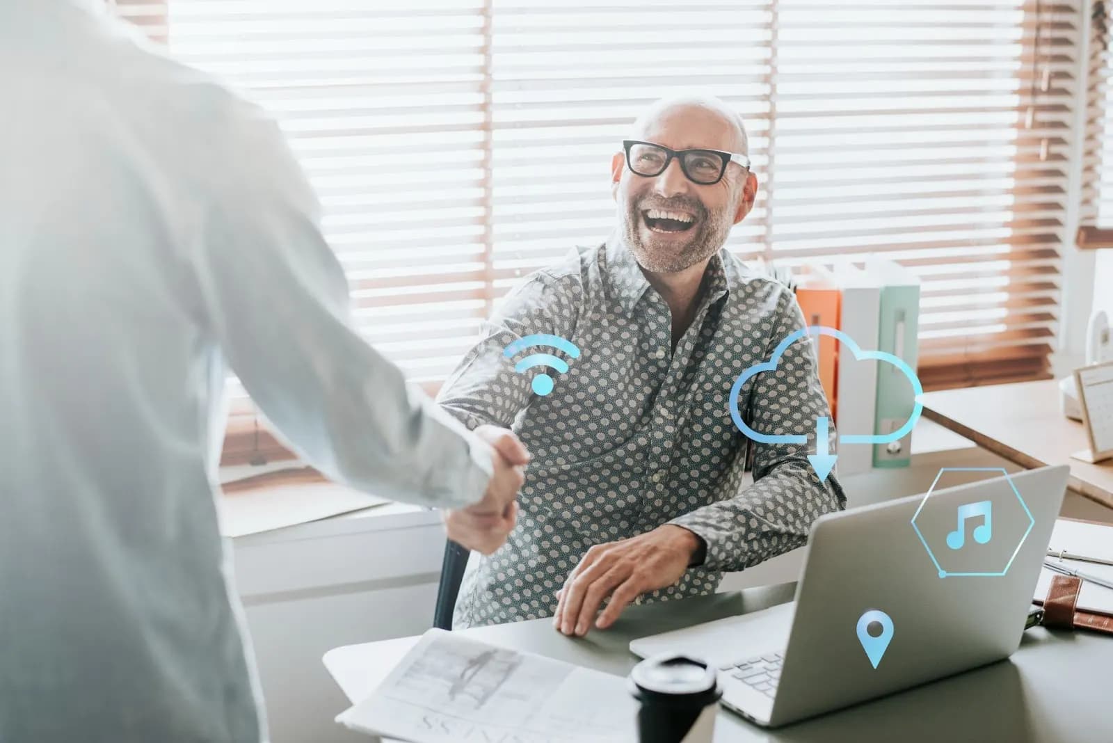 Two professionals shaking hands in an office with cloud and connectivity icons overlaying the scene, symbolizing successful collaboration and seamless data exchange.