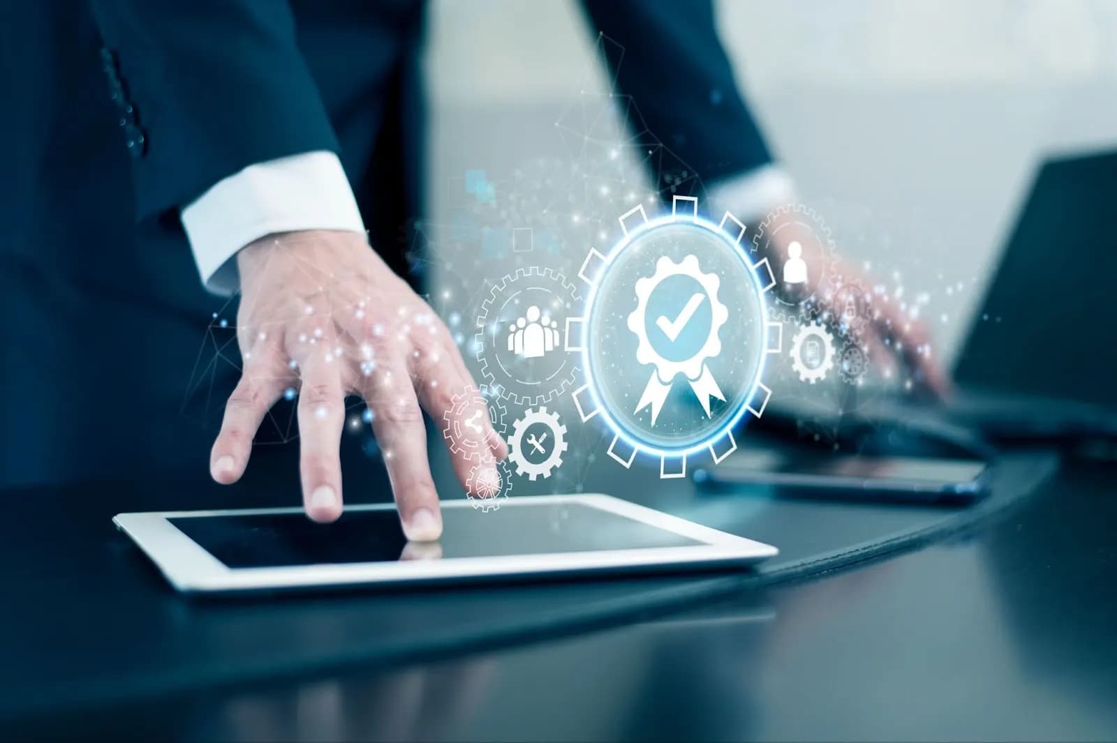 Close-up of hands using a tablet to control a digital workflow, represented by a holographic gear and checkmark, illustrating automated business processes.
