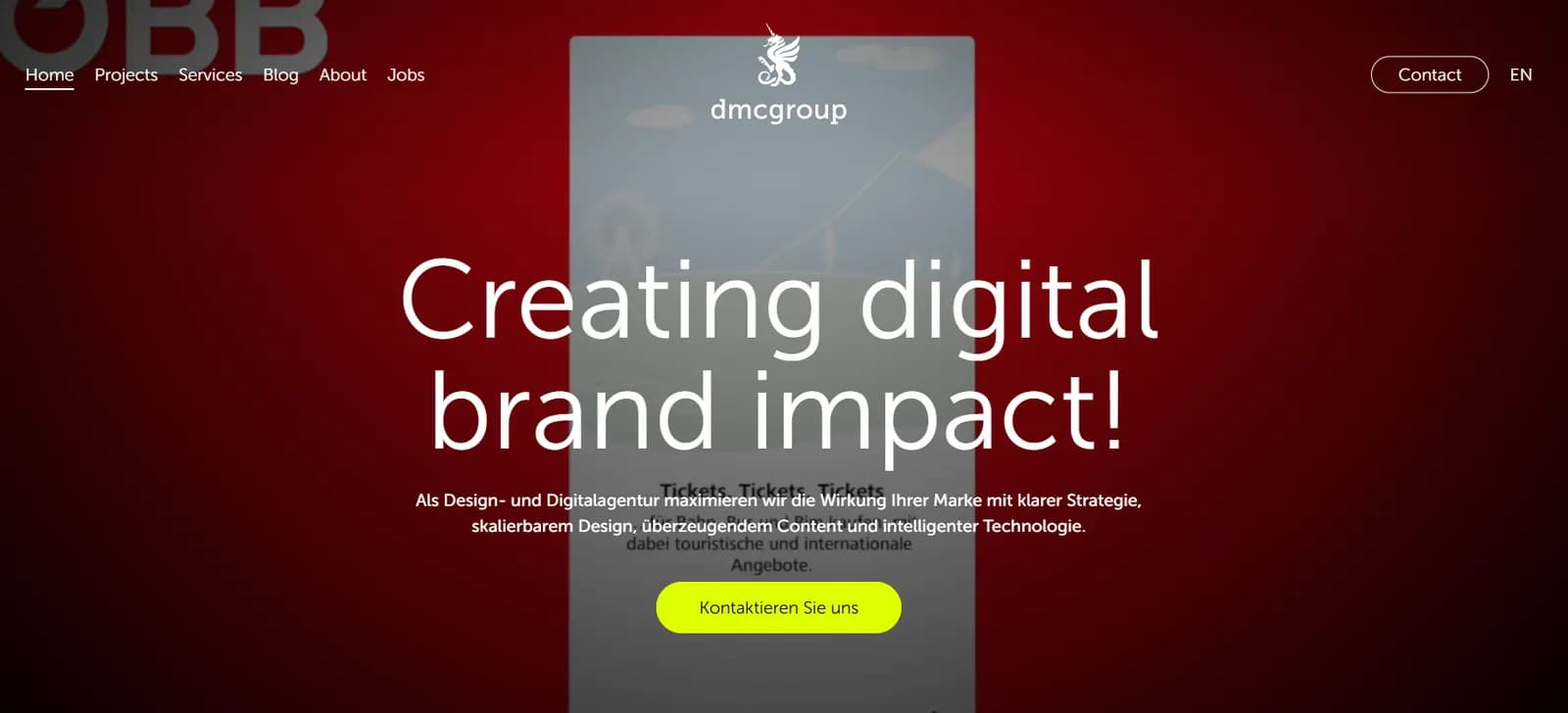 DMCgroup website with the slogan 'Creating digital brand impact' and a mobile app application in the background